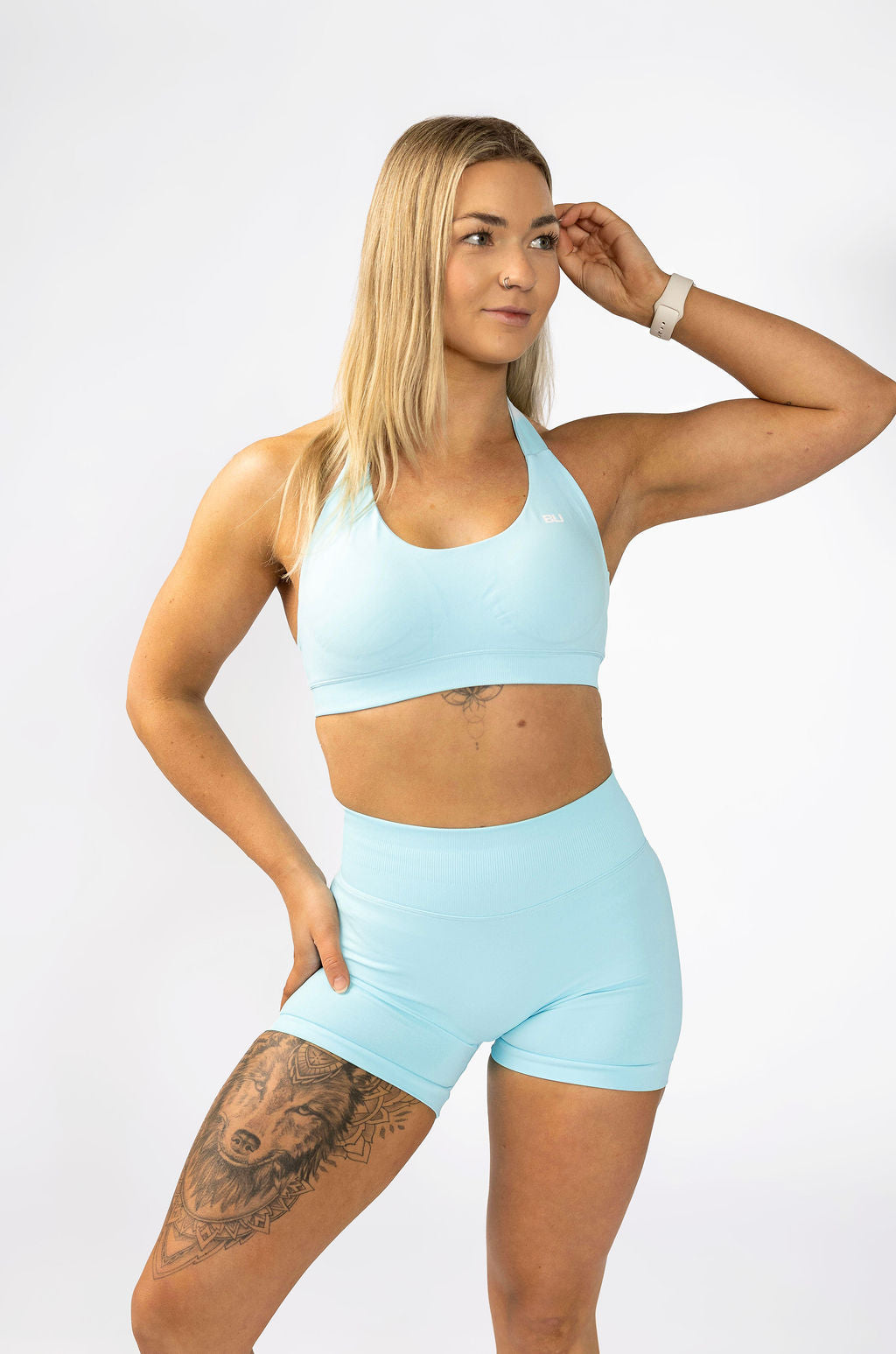Woman wearing Aqua sculpt halter sports bra with V-neckline and medium support with matching aqua shorts