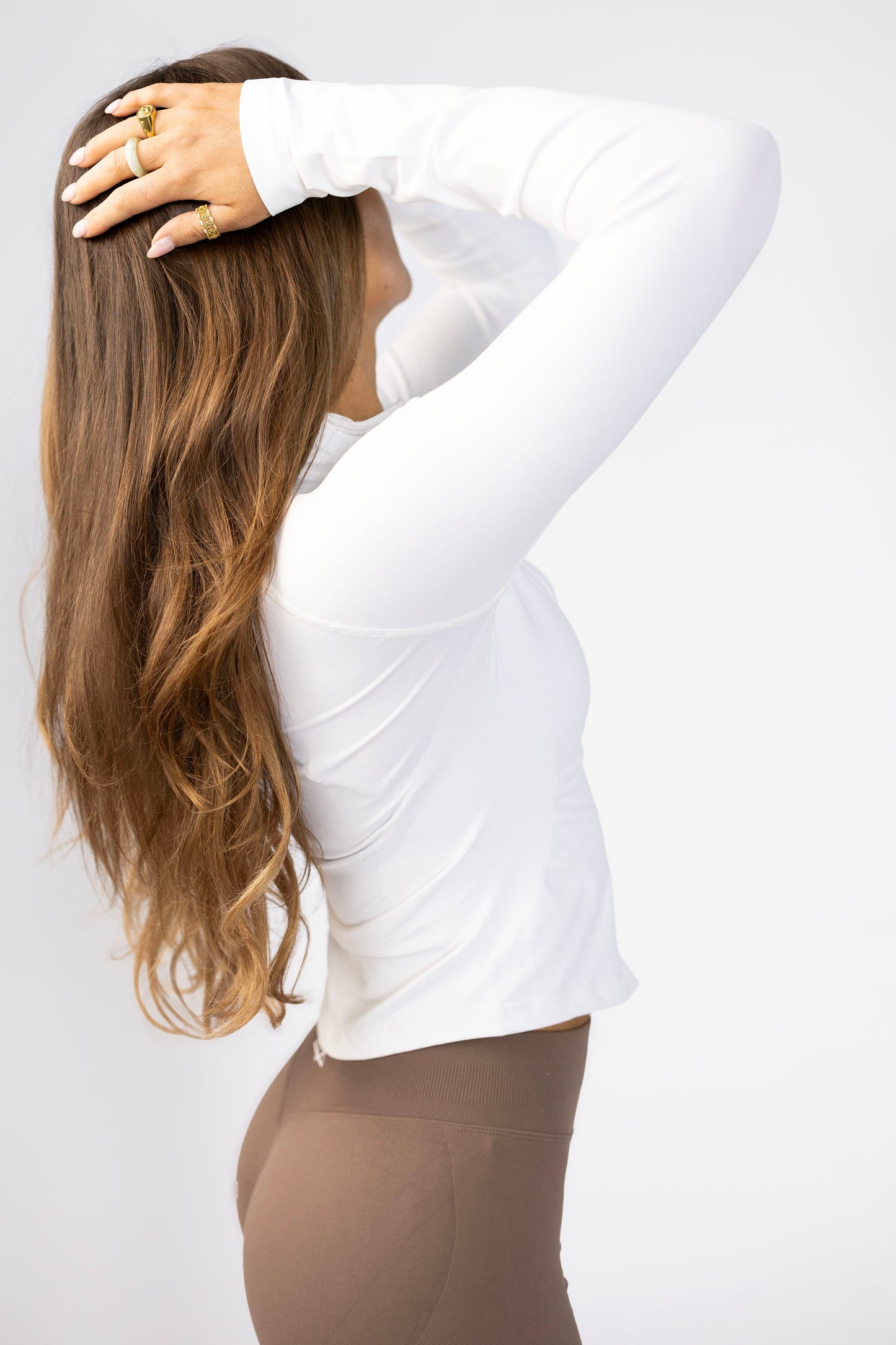Side view of white full zip jacket displaying athletic cut and breathable fabric. Paired with coffee shorts